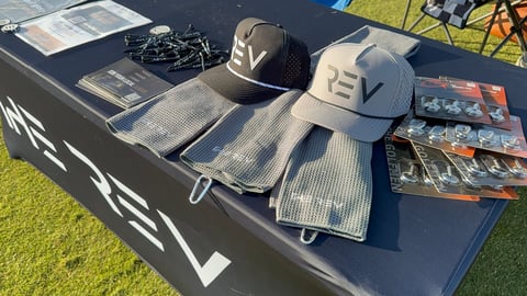 Outdoor EV merchandise display with branded caps, t-shirts, and promotional materials