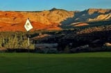 Golf flag on green fairway with red rock mountains and desert landscape in the background